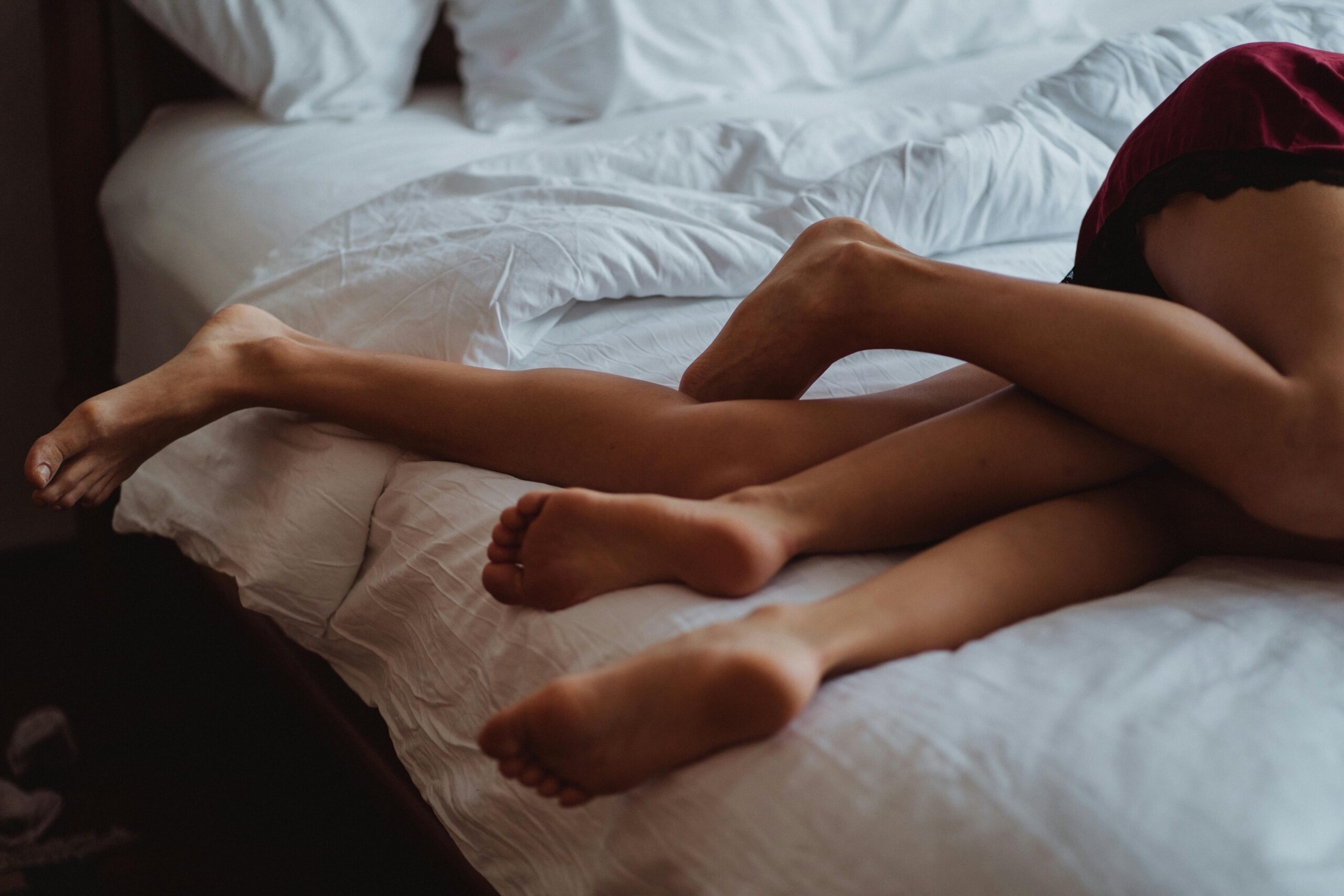 To elskere i en intim stilling i sengen – illustrerer nærhet, kommunikasjon og felles nytelse med sexleketøy som dobbeltdildo.