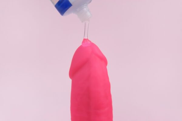 Glidemiddel som påføres en rosa dildo – illustrasjon av riktig bruk og valg av glidemiddel for sexleketøy.