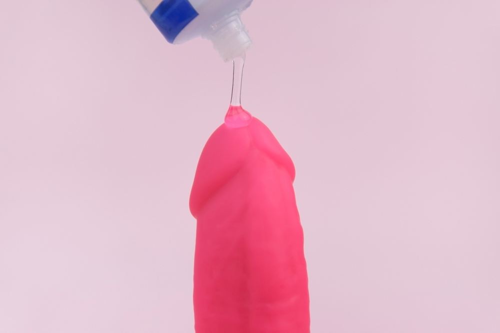 Glidemiddel som påføres en rosa dildo – illustrasjon av riktig bruk og valg av glidemiddel for sexleketøy.