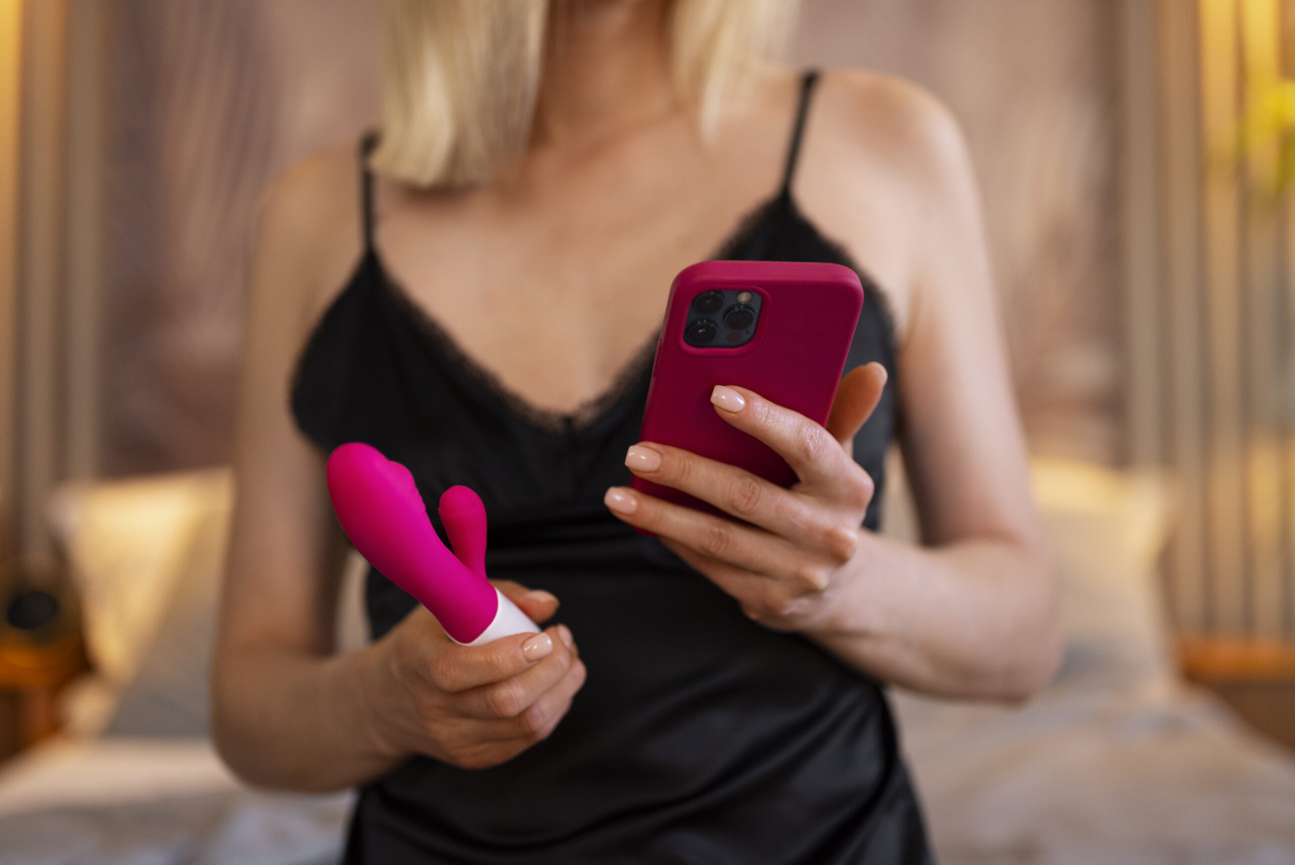 Kvinne holder rabbitvibrator og mobil – illustrerer appstyrt kombinasjonsvibrator med moderne funksjoner for tilpasset nytelse.